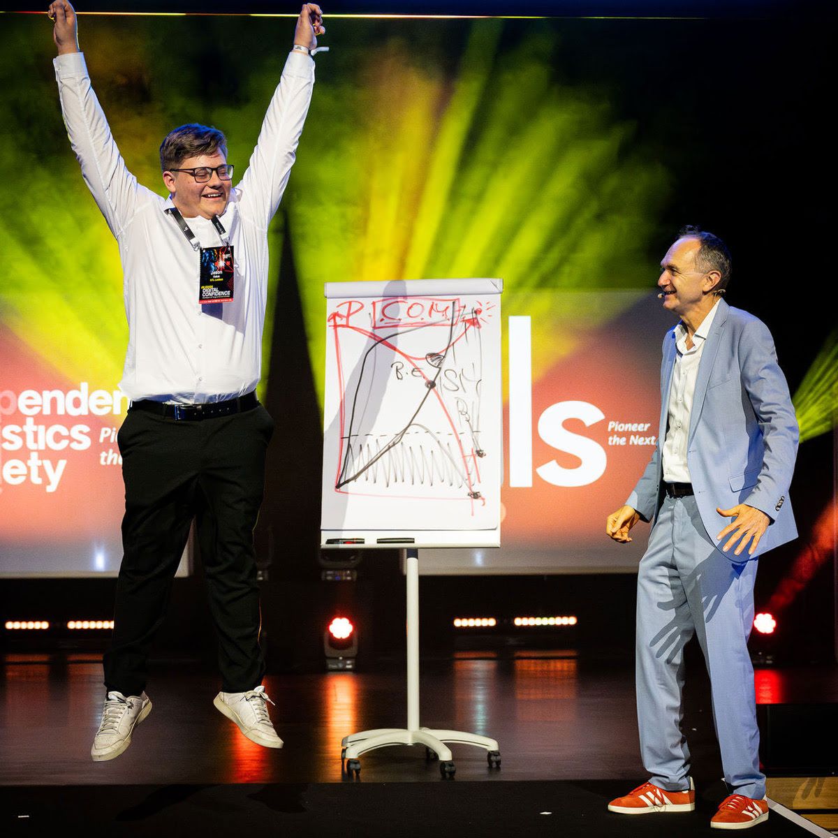 Ein Mann aus dem Publikum macht fröhlich Klimzüge auf der Bühne neben Otmar Kastner und einem Whiteboard