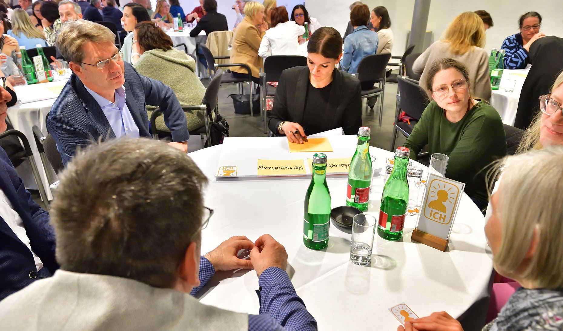 Bei einem High Impact Training sitzen die Teilnehmenden um einen Rnden Tisch und erfüllen zusammen eine Aufgabe.